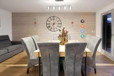 a dining room with a table and chairs and a clock at Taragan - Totally Refurbished 3 bed apt, Central St Gervais! in Saint-Gervais-les-Bains