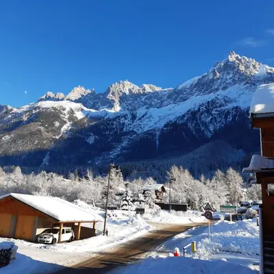 a snow covered mountain in the distance with a house at Appartement Chamonix Bossons in Chamonix-Mont-Blanc