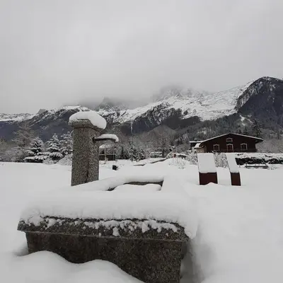 a yard covered in snow with mountains in the background at Appartement Chamonix Bossons in Chamonix-Mont-Blanc