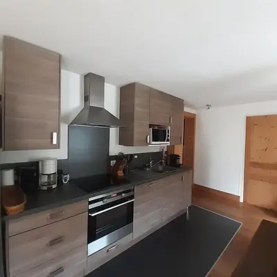 a kitchen with stainless steel appliances and wooden cabinets at Appartement Chamonix Bossons in Chamonix-Mont-Blanc