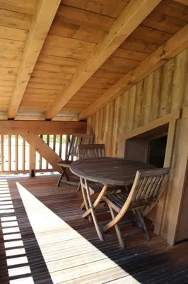 a wooden porch with a table and two chairs at RESIDENCE SASKYA in Samoëns