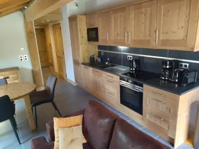 a kitchen with wooden cabinets and a couch and a table at RESIDENCE SASKYA in Samoëns