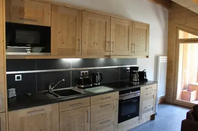 a kitchen with wooden cabinets and a sink and a stove at RESIDENCE SASKYA in Samoëns