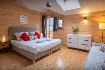 a bedroom with wooden walls and a bed with red pillows at Chalet Choquette - OVO Network in Les Houches
