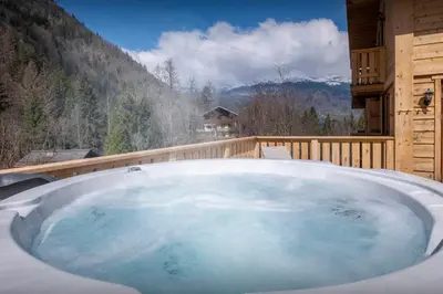 a jacuzzi tub on a balcony with a mountain at Chalet Choquette - OVO Network in Les Houches
