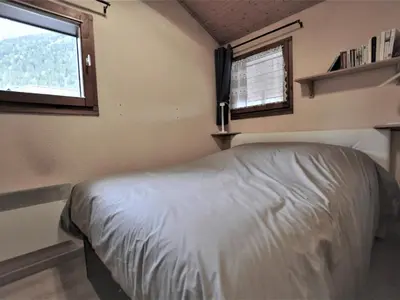 a small bedroom with a bed and two windows at Chamonix: Charmant 2 pièces avec parking proche centre - FR-1-517-66 in Chamonix-Mont-Blanc