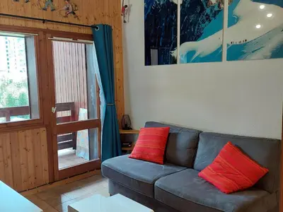a living room with a couch with two red pillows at Chamonix: Charmant 2 pièces avec parking proche centre - FR-1-517-66 in Chamonix-Mont-Blanc