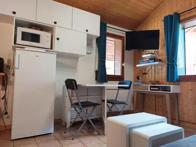 a kitchen with a refrigerator and a table with a microwave at Chamonix: Charmant 2 pièces avec parking proche centre - FR-1-517-66 in Chamonix-Mont-Blanc