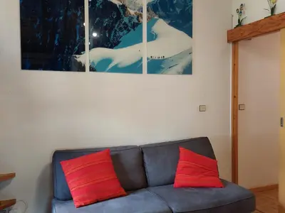 a couch with two red pillows in a living room at Chamonix: Charmant 2 pièces avec parking proche centre - FR-1-517-66 in Chamonix-Mont-Blanc