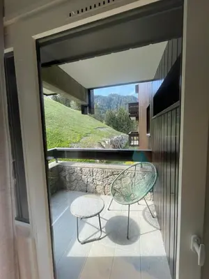 a glass table and a chair on a balcony at Le LihamWood in Megève