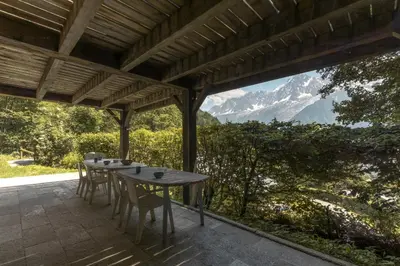 a table and chairs on a patio with a view of a mountain at Datcha of Sky -Jardin - Calme - 180 vues - 9 chambres & Studio Appt in Les Houches