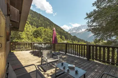 a deck with tables and chairs with mountains in the background at Datcha of Sky -Jardin - Calme - 180 vues - 9 chambres & Studio Appt in Les Houches