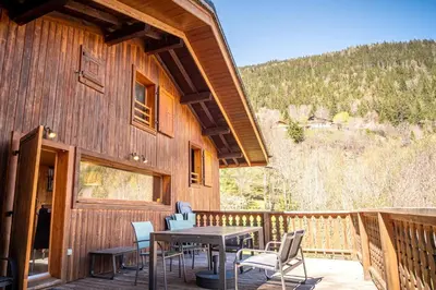 a deck with a table and chairs on a cabin at Datcha of Sky -Jardin - Calme - 180 vues - 9 chambres & Studio Appt in Les Houches