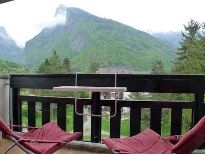 a couple of chairs sitting on a balcony with mountains at 2 pièces confortable & lumineux au centre de Samoëns - Animaux admis et parking inclus - FR-1-629-126 in Samoëns
