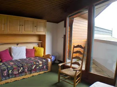 a bedroom with a bed with colorful pillows and a chair at 2 pièces confortable & lumineux au centre de Samoëns - Animaux admis et parking inclus - FR-1-629-126 in Samoëns