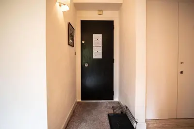 a hallway with a black door with a sign on it at Les Aiguilles du Brevent - Grand Appt Renove - Central - Terrasse avec Vue in Chamonix-Mont-Blanc
