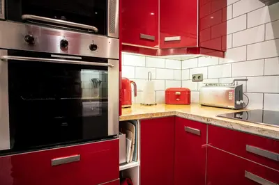 a kitchen with red cabinets and a black oven at Les Aiguilles du Brevent - Grand Appt Renove - Central - Terrasse avec Vue in Chamonix-Mont-Blanc
