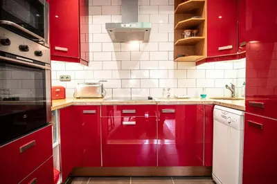 a red kitchen with white appliances and red cabinets at Les Aiguilles du Brevent - Grand Appt Renove - Central - Terrasse avec Vue in Chamonix-Mont-Blanc