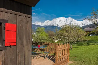 a wooden deck with a table and chairs and mountains at Le Mazot de Janton in Combloux