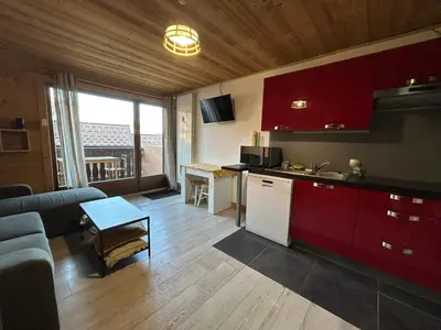 a kitchen with red cabinets and a living room at Studio équipé / centre station in Les Carroz d'Araches
