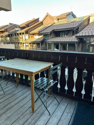 a wooden table and chairs on a deck with buildings at Studio équipé / centre station in Les Carroz d'Araches