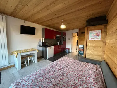 a bedroom with a bed and a table and a kitchen at Studio équipé / centre station in Les Carroz d'Araches