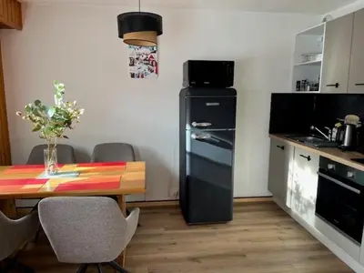 a kitchen with a table and a black refrigerator at Cosy Criou - Appartement avec vue sur la montagne in Samoëns