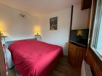 a bedroom with a red bed and a flat screen tv at Cosy Criou - Appartement avec vue sur la montagne in Samoëns
