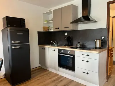 a kitchen with a black refrigerator and white cabinets at Cosy Criou - Appartement avec vue sur la montagne in Samoëns