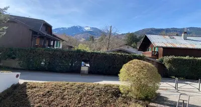 a house with a hedge in front of a driveway at Cosy Criou - Appartement avec vue sur la montagne in Samoëns