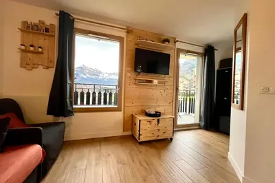 a living room with a couch and a tv and two windows at Refuge des Prés in Saint-Gervais-les-Bains