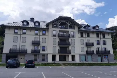 a large white building with cars parked in a parking lot at Refuge des Prés in Saint-Gervais-les-Bains