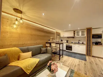 a living room with a couch and a kitchen at Évasion Parfaite in Chamonix-Mont-Blanc