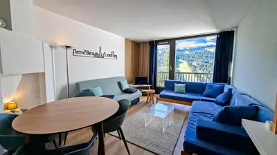a living room with a blue couch and a table at Appartement Flaine Forêt in Flaine