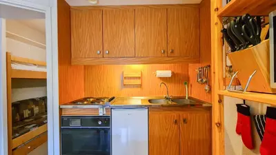 a small kitchen with wooden cabinets and a sink at Appartement Flaine Forêt in Flaine