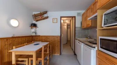 a kitchen with wooden cabinets and a table with chairs at Grand Morillon 116 - Appt pied des pistes - 5 pers in Morillon