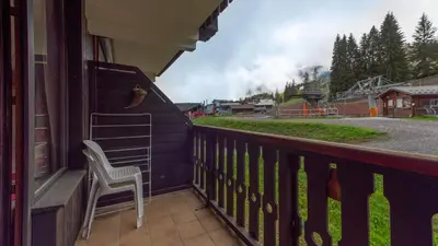 a chair on a balcony with a view of a train at Grand Morillon 116 - Appt pied des pistes - 5 pers in Morillon