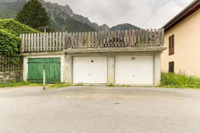 a building with two garage doors and a fence at L'Ecrin des Pècles - Centrale - Rénové - Immense Terrasse Face au Mont-Blanc in Chamonix-Mont-Blanc