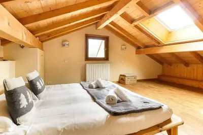 a large bed in a room with wooden ceilings at L'Ecrin des Pècles - Centrale - Rénové - Immense Terrasse Face au Mont-Blanc in Chamonix-Mont-Blanc