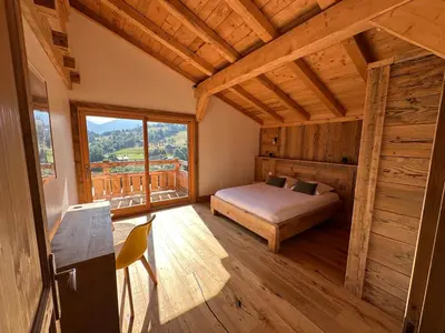 a bedroom with a bed and a large window at Chalet vue Mont Blanc avec jacuzzi extérieur in Combloux