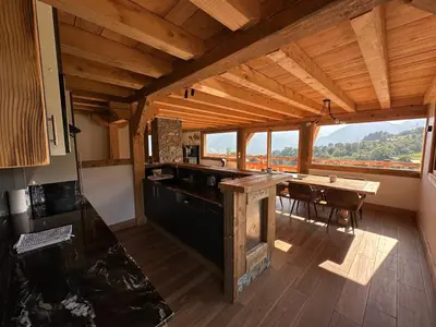 a kitchen with a table and a large window at Chalet vue Mont Blanc avec jacuzzi extérieur in Combloux