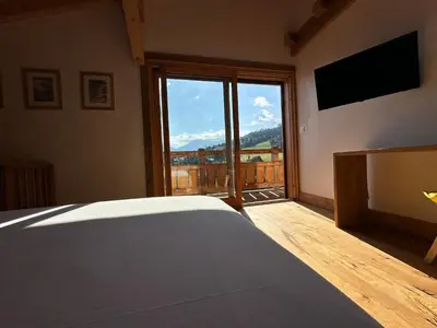a bedroom with a bed and a large window at Chalet vue Mont Blanc avec jacuzzi extérieur in Combloux