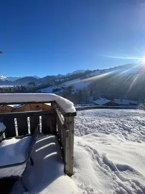 a bench covered in snow with the sun in the background at Chalet vue Mont Blanc avec jacuzzi extérieur in Combloux