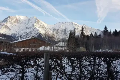 a barn with snow covered mountains in the background at Mon refuge face au Mont Blanc in Saint-Gervais-les-Bains