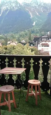 a table and two stools on a balcony with a mountain at Studio élégant à Chamonix in Chamonix-Mont-Blanc
