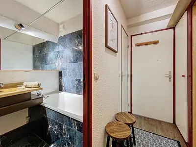 a bathroom with a tub and a sink and a stool at P'tiot Chamois Appartement Chamonix, Parking in Chamonix-Mont-Blanc