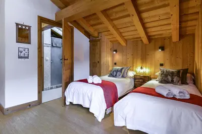 two beds in a room with wooden walls and wooden floors at Chalet Chardonnet in Chamonix-Mont-Blanc
