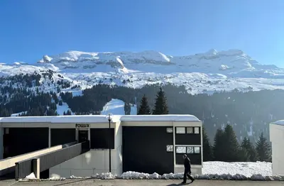 a man walking past a building with a snow covered mountain at Résidence Gemeaux - Studio confortable · Centre station · Balcon MAE-7844 in Magland