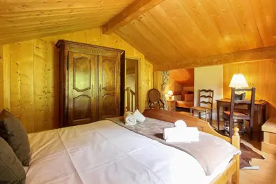 a bedroom with a large bed with wooden walls at Chalet de charme - 8 pers - 140m2 - Jardin - Calme in Les Houches