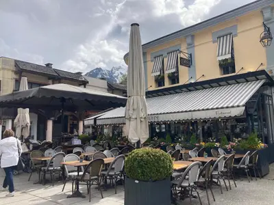 a patio with tables and chairs with an umbrella at Abeille de Chamonix in Chamonix-Mont-Blanc